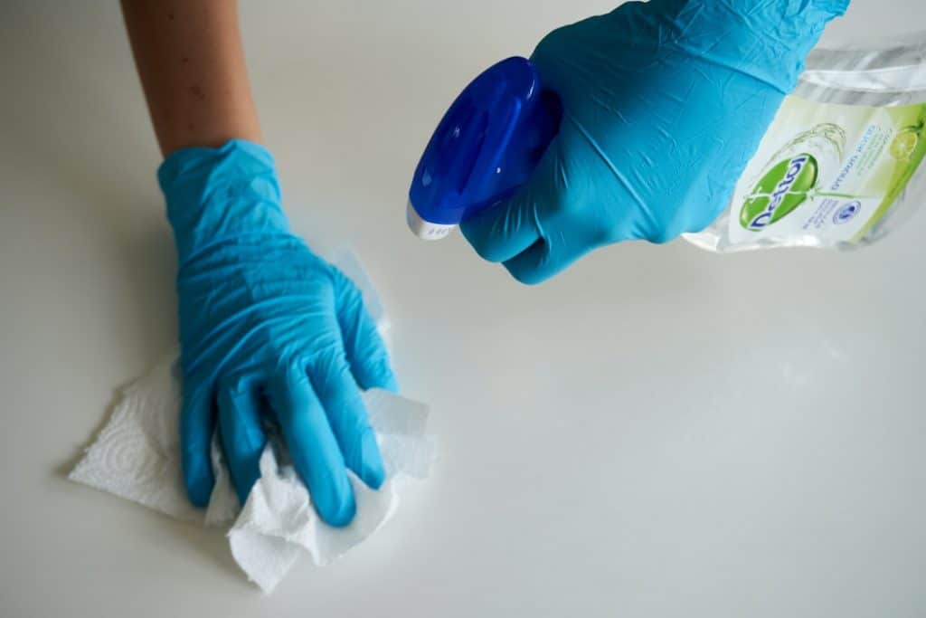 person blue gloves spraying surface